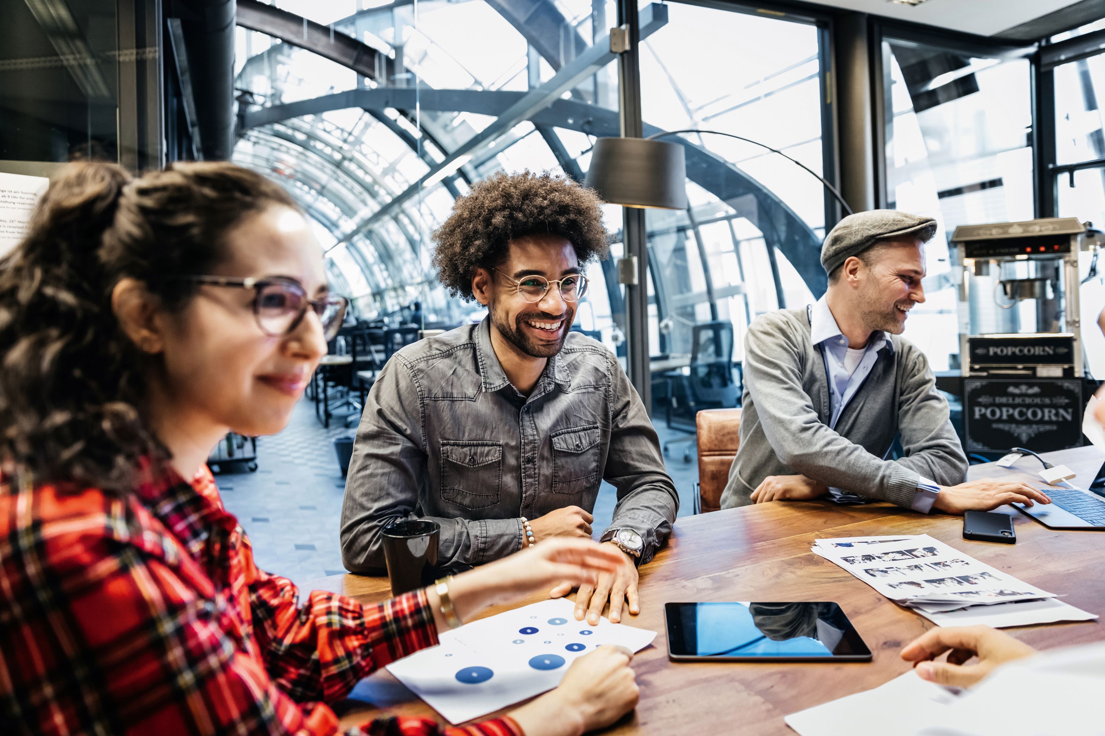 Eine Gruppe von jungen Leuten sitzt in einem Café und brainstormen zusammen über Projekte.